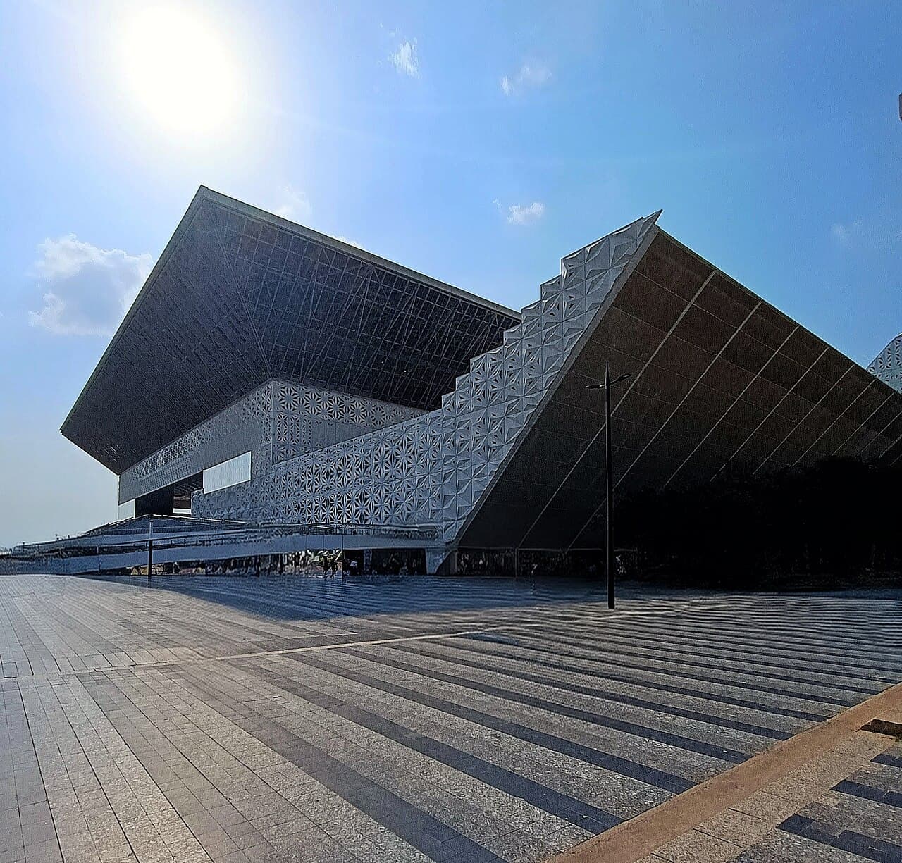 The YASHOBHOOMI (IICC) convention centre in Dwarka, New Delhi — a large curved glass and stone facade lit at dusk.